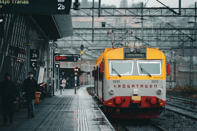 A vibrant train at Jönköping station on a cloudy day in Sweden, capturing Nordic architecture. Svenska städer: lokal service, krav och upphandling